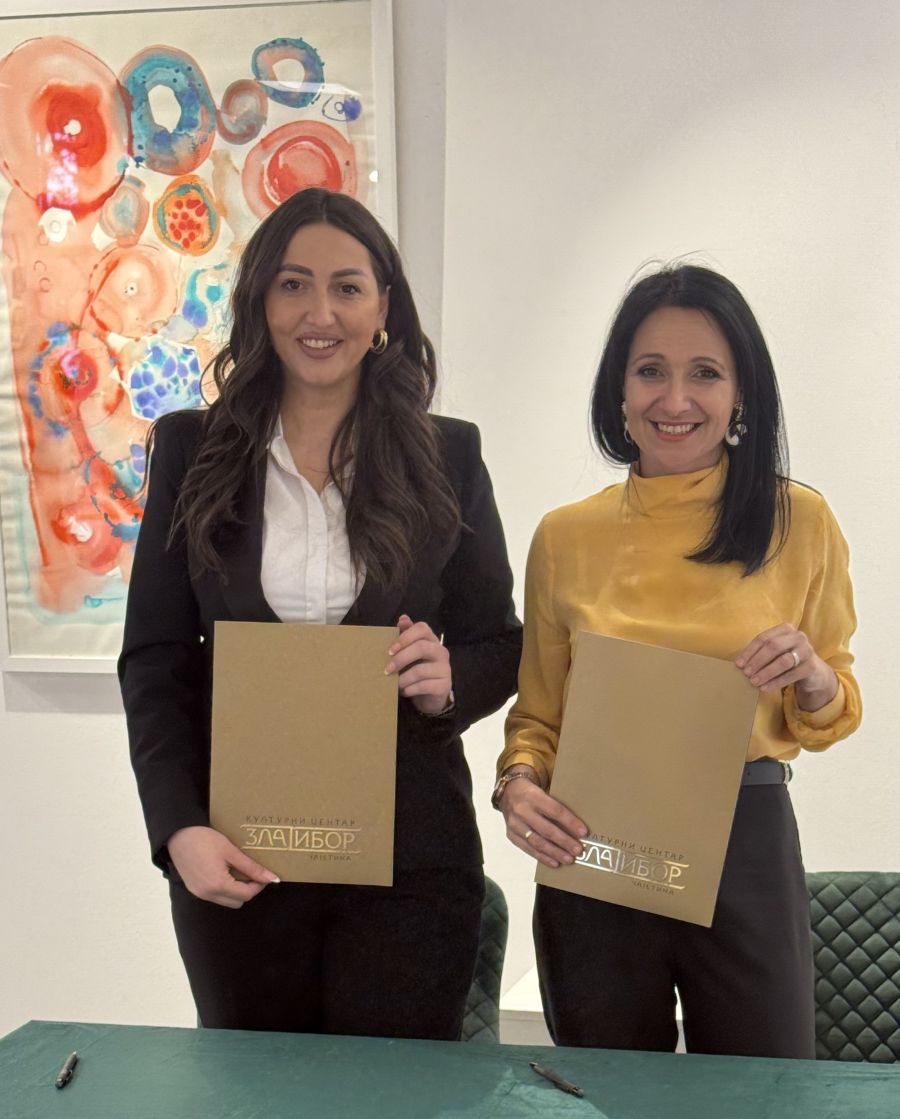 dve zene stoje i drze fascikle ispred sebe