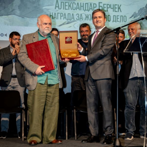 muskarac dodejuje plaketu drugom muskarcu na sceni