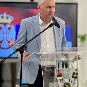 Čovek stoji i govori na mikrofon