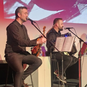 muskarac sedi i peva, držeći violinu