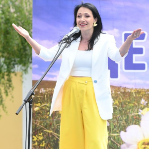 zena u beloм sakou i zutim pantalonama govori na mikrofon