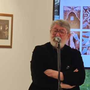 muskarac u crnom stoji i prica na mikrofon