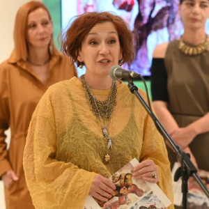 zena vatrene kose u zutom govori na mikrofon