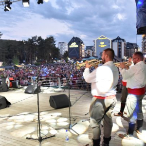 muzicari sviraju u trube iza se vidi publika