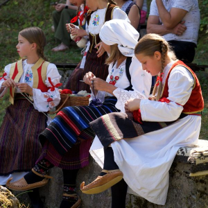 zena i devojcice u narodnoj nosnji pletu
