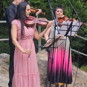 dve zene sviraju, muskarac se vidi u pozadini