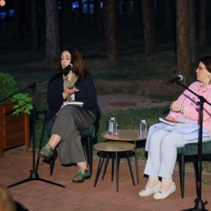 dve zene sede i govore u mikrofon