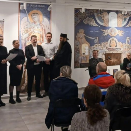 ljudi sede i slusaju mešoviti hor, pod vođstvom sveštenika