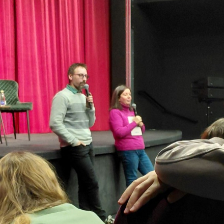 muskarac i zena stoje naslonjeni na binu  