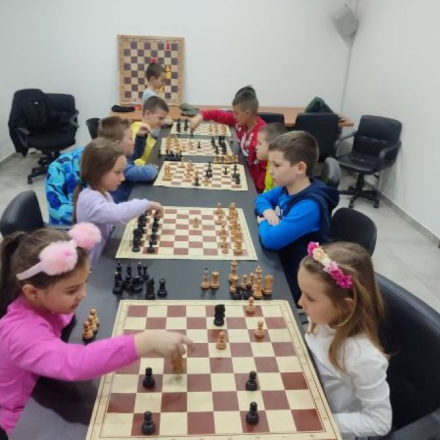 deca sede za stolovima i igraju sah